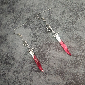 Macro shot of silver dagger earrings with red blood stains for Halloween theme decor