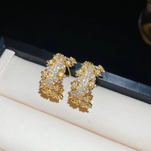 Detailed macro view of gold-plated C-shaped earrings with shimmering pave zircon stones