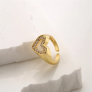 Detailed macro shot of a gold heart ring with white zircons on a white stone base