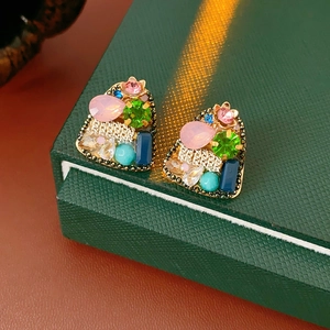 Detail of vintage gold-plated earrings with multi-colored crystals on green box