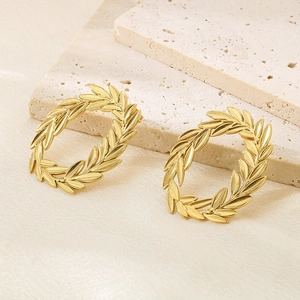 Close-up of 18k gold-plated stainless steel laurel leaf hoop earrings on stone background