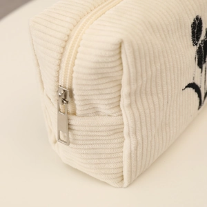 Detail of cream corduroy fabric texture and silver metal zipper on floral makeup bag