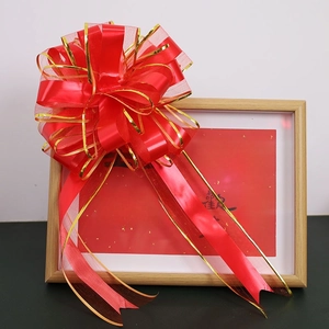 Close-up of a large red wedding bow with gold edges on a wooden frame for gift wrapping