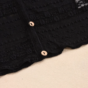 Close-up of black lace fabric texture with circular wooden buttons and intricate patterns