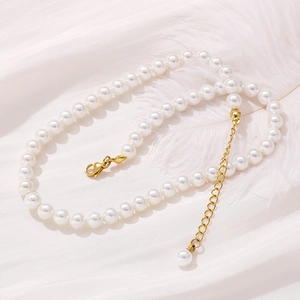 Detail of white pearl necklace with gold lobster clasp and extension chain on white feathers