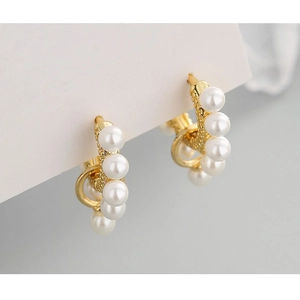 Detail view of elegant S925 silver gold hoop earrings with white pearls on a white card