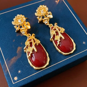 Detail of vintage flower earrings with red water-drop gems on a navy jewelry box