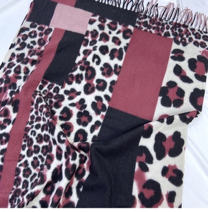 Close-up of leopard print scarf featuring pink color block stitching and tassel details