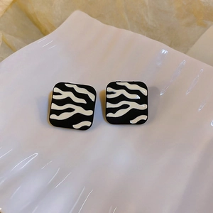 Gros plan de boucles d'oreilles carrées motif zèbre avec placage en or sur plateau