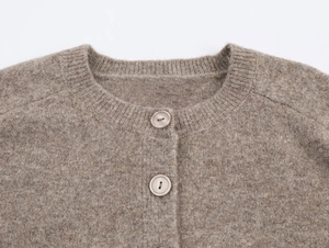 Detailed macro view of the soft brown knit fabric and matching round buttons