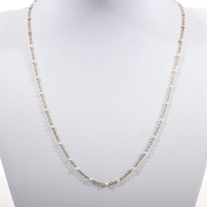Close-up of golden stainless steel beaded chain with white enamel droplet details