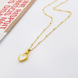 Detailed close-up of a gold scallop-edged heart pendant with a white shell inlay