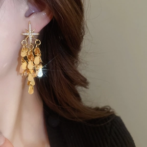 Gros plan de boucles d'oreilles étoiles dorées avec glands en zircone sur un modèle