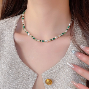 Detailaufnahme der Perlenkette mit grünen Edelsteinen und goldfarbenen Zwischenstücken
