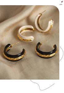 Detail of C-shaped enamel hoop earrings in black and cream white with gold edges