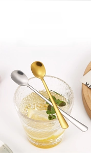 Detail of stainless steel spoons in silver and gold finish placed inside a water glass