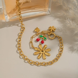 Detailed shot of an 18K gold chain bracelet with cherry, daisy, and heart charms
