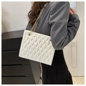 Detail of white quilted handbag featuring premium glossy texture and gold chain strap