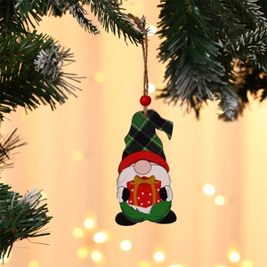 Detail of wooden gnome Christmas ornament with gift box hanging on a tree branch