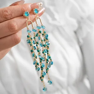 Golden tassel earrings with sea blue faceted crystals and turquoise beads in hand view