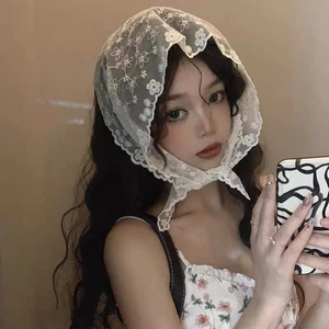 Close-up of white triangle lace headscarf with delicate floral embroidery and scalloped edges
