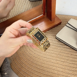 Detail of a gold rectangular quartz watch with leopard print mesh strap and black dial
