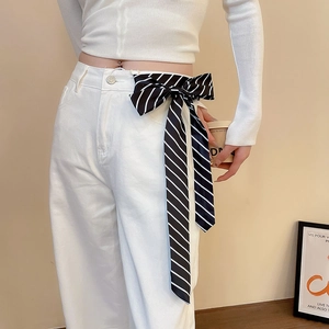 Detail showing a black and white striped silk scarf used as a stylish belt on white jeans