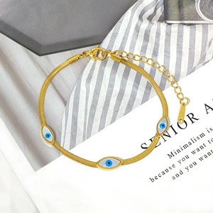 Golden titanium steel snake chain bracelet featuring blue evil eye charms on a stripe background
