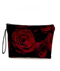 Detail view of the black makeup bag featuring a red rose pattern and wrist strap