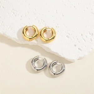 Polished C-shape 14K gold and silver chunky hinged hoop earrings on textured stone