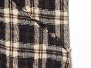 Macro shot of plaid fabric detailing with classic fringes and woven texture in warm tones