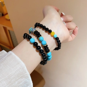 Close-up of turquoise and black agate beaded bracelets worn on a wrist in warm lighting