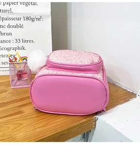 Pink cartoon kids backpack with glitter bunny ears on a wooden surface detail view