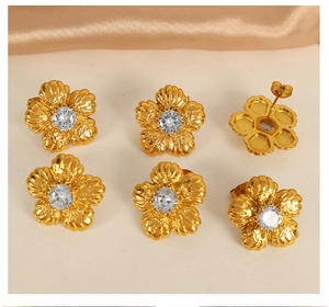 Detailed view of three pairs of vintage gold flower earrings with crystals on satin