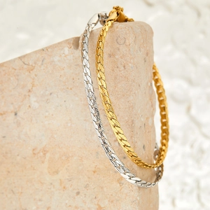 Gold and silver stainless steel Cuban link bracelets displayed on a textured stone base