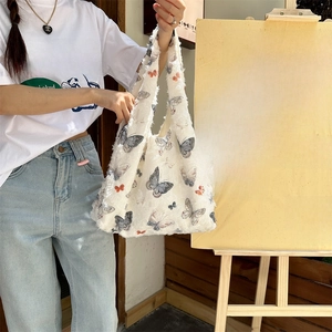Close-up of white plush tote bag featuring colorful butterfly patterns and fuzzy texture