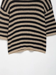 Détail de la maille épaisse et des rayures classiques noires et jaunes sur le pull