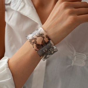 Detailed macro view of wide acrylic cuff bracelet with black rose lace pattern inlay