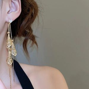 Close-up of elegant gold tassel earrings with hollow cone pendants worn by a model