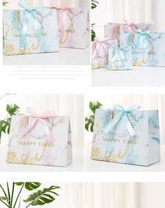 Detail of marble pattern gift bags with ribbon bows and Happy Times gold foil print
