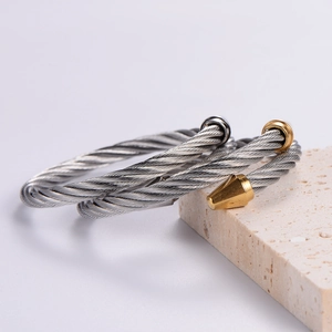 Twisted steel wire bracelet with silver and gold cone ends on stone background