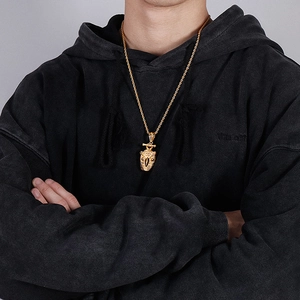 Detailed view of a gold owl pendant on a twist chain worn by a model in black apparel
