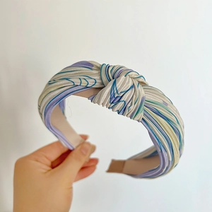 Detail view of silk-textured knotted headband featuring blue and purple linear patterns