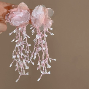 Detail of pink organza flower earrings with handcrafted beaded tassels in a long fringe style