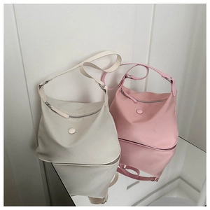 Détail de sacs bandoulière en nylon spacieux en beige et rose sur surface miroir