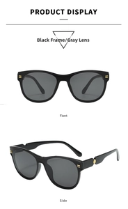 Close-up of black oval sunglasses with golden metal rivets and grey lenses