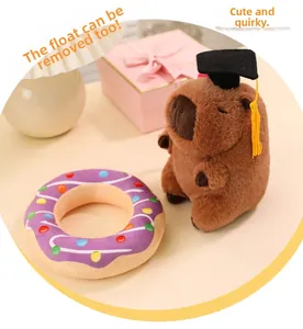 Detail of capybara plush toy with removable purple donut ring and graduation cap