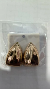 Detail view of teardrop gold metal earrings inside protective clear plastic packaging