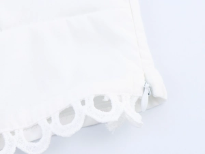Détail de la dentelle blanche brodée et de la fermeture éclair invisible sur le haut chic