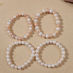 Elastic natural freshwater pearl bracelets in white and peach orange colors on beige background